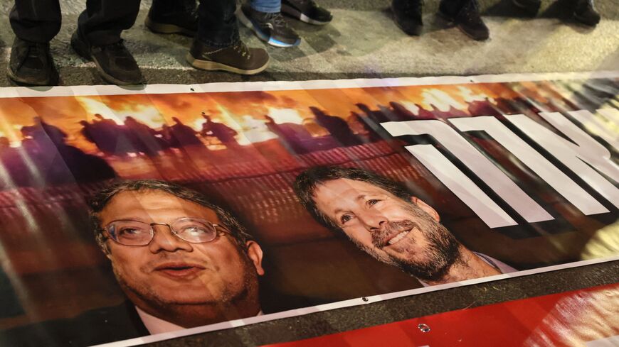 Israelis stand next to a poster with the portraits of Minister of National Security Itamar Ben-Gvir and Finance Minister Bezalel Smotrich during a protest against the government's controversial justice reform bill in Tel Aviv on March 4, 2023. (Photo by JACK GUEZ / AFP) (Photo by JACK GUEZ/AFP via Getty Images)